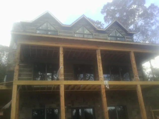 Dormers and porch framing on a large log home under construction — Roof Coating work by our crew in Burnham