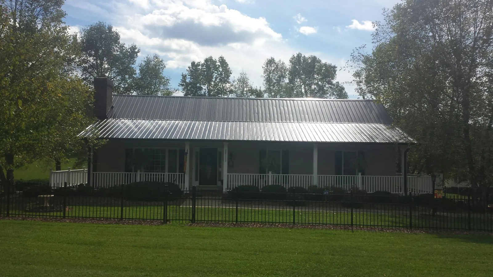 Gray metal roof on a brick ranch with a full width front porch — Gutter Guard Installation work by our crew in Burnham